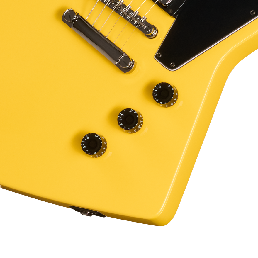 Close-up of a yellow electric guitar with black control knobs on a white background