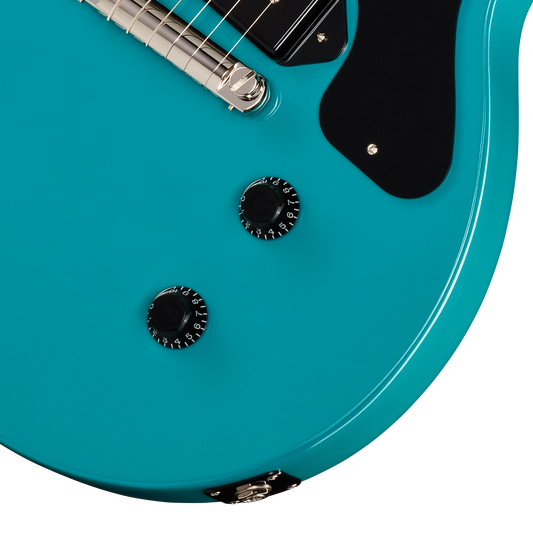 Close-up of a turquoise electric guitar with control knobs on a white background