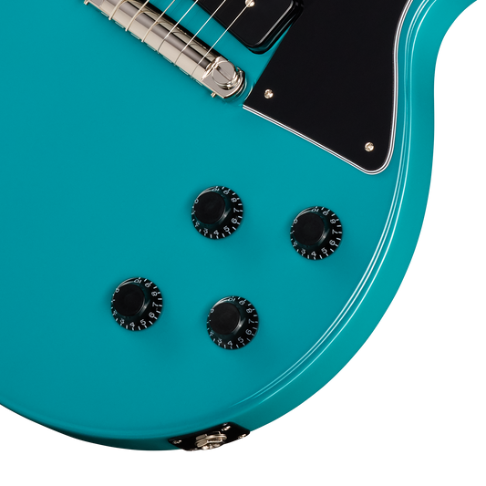 Close-up of a turquoise electric guitar with control knobs on a white background