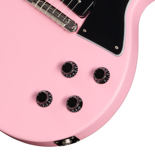 Close-up of a pink electric guitar with black pickguard and tuning pegs.